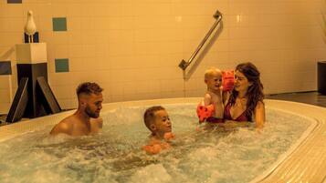 Une famille dans un jacuzzi, avec un mur carrelé et une main courante en arrière-plan.