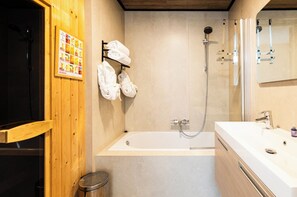 Een moderne badkamer met een badkuip, douche en een houten wand met een handdoekhouder.