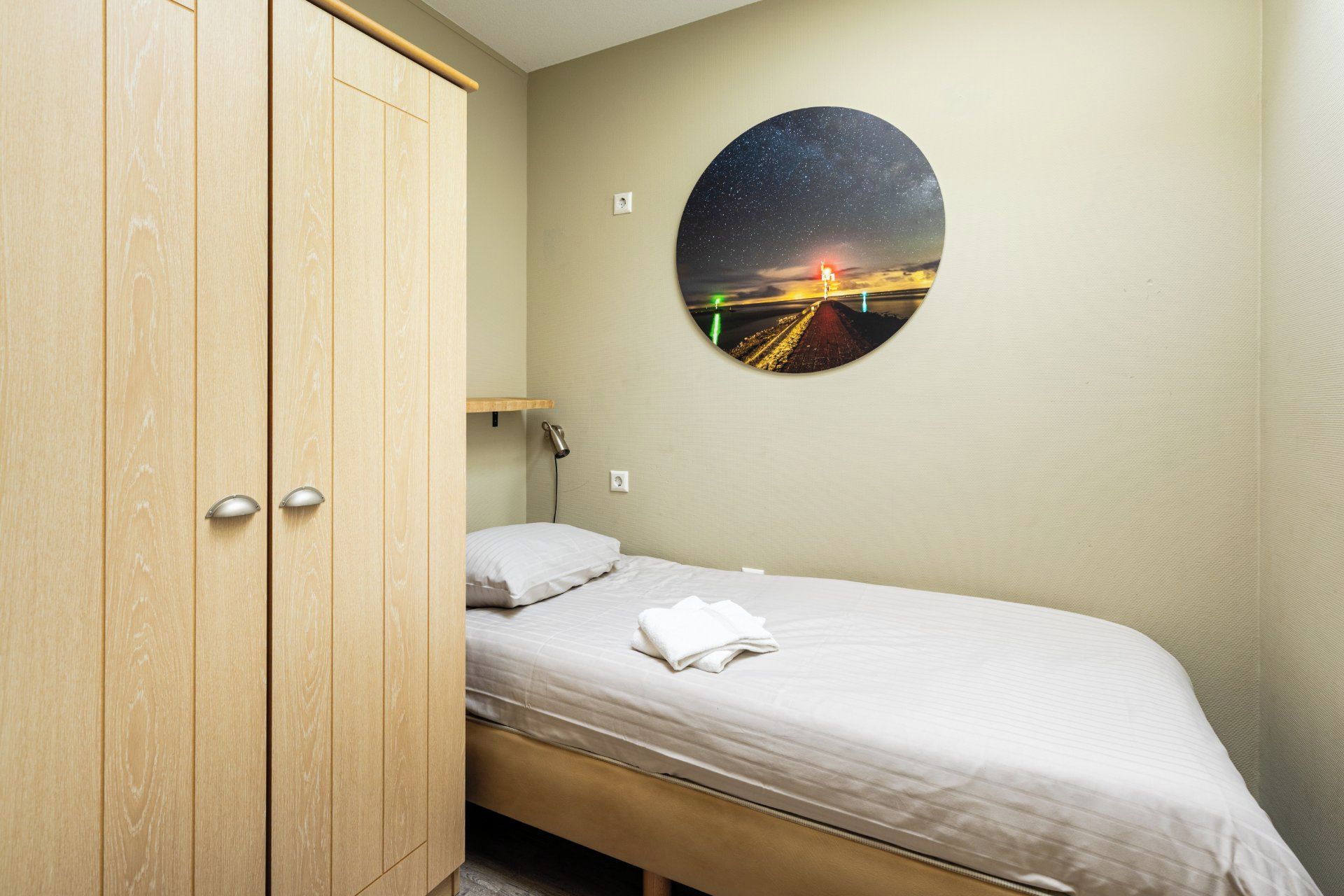 A bedroom with a bed, a wooden wardrobe, a night sky mural, and a night light.