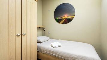 A bedroom with a bed, a wooden wardrobe, a night sky mural, and a night light.