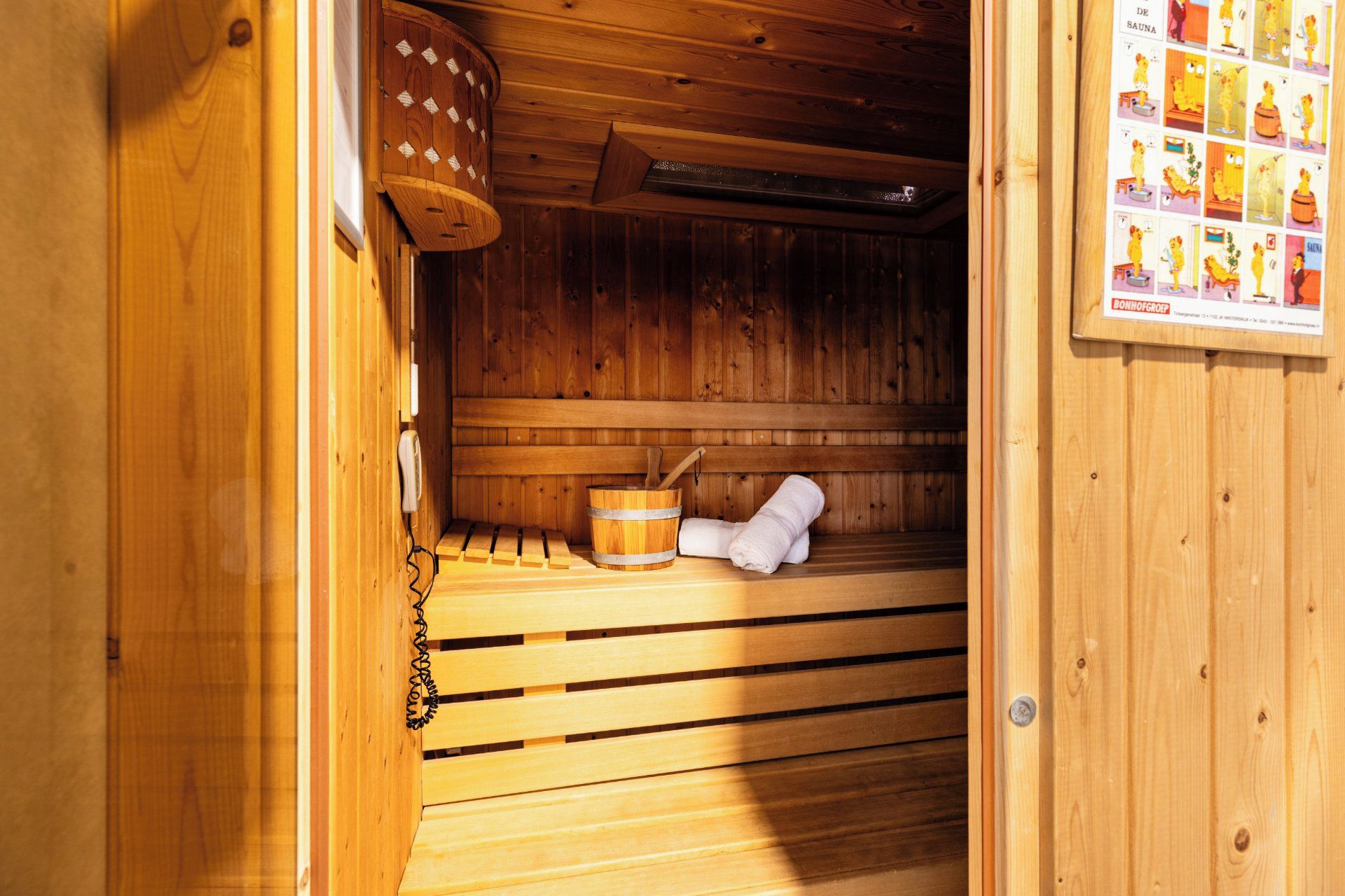 Sauna, jossa on puiset lauteet, puinen ämpäri ja pyyhe.
