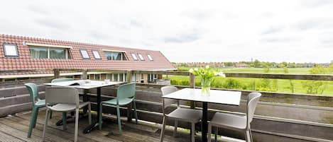 Een terras buiten met een tafel en stoelen, met uitzicht op een landelijk gebied.