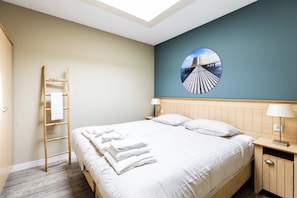 Een hotelkamer met een bed, een houten trap, een nachtkastje, een lamp en een ronde wanddecoratie.