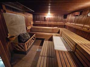 Un sauna avec des bancs en bois et un poêle en pierre.