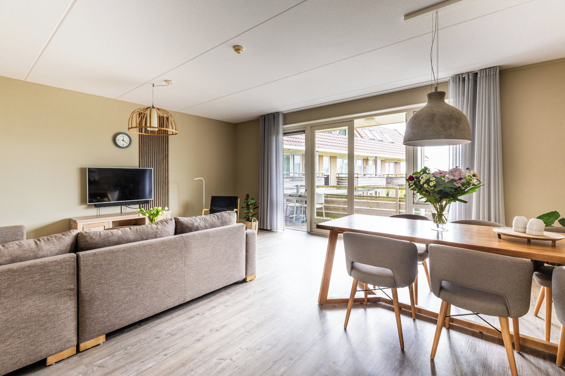 Un salon moderne comprenant un canapé, un téléviseur et un coin repas avec des chaises et une table.