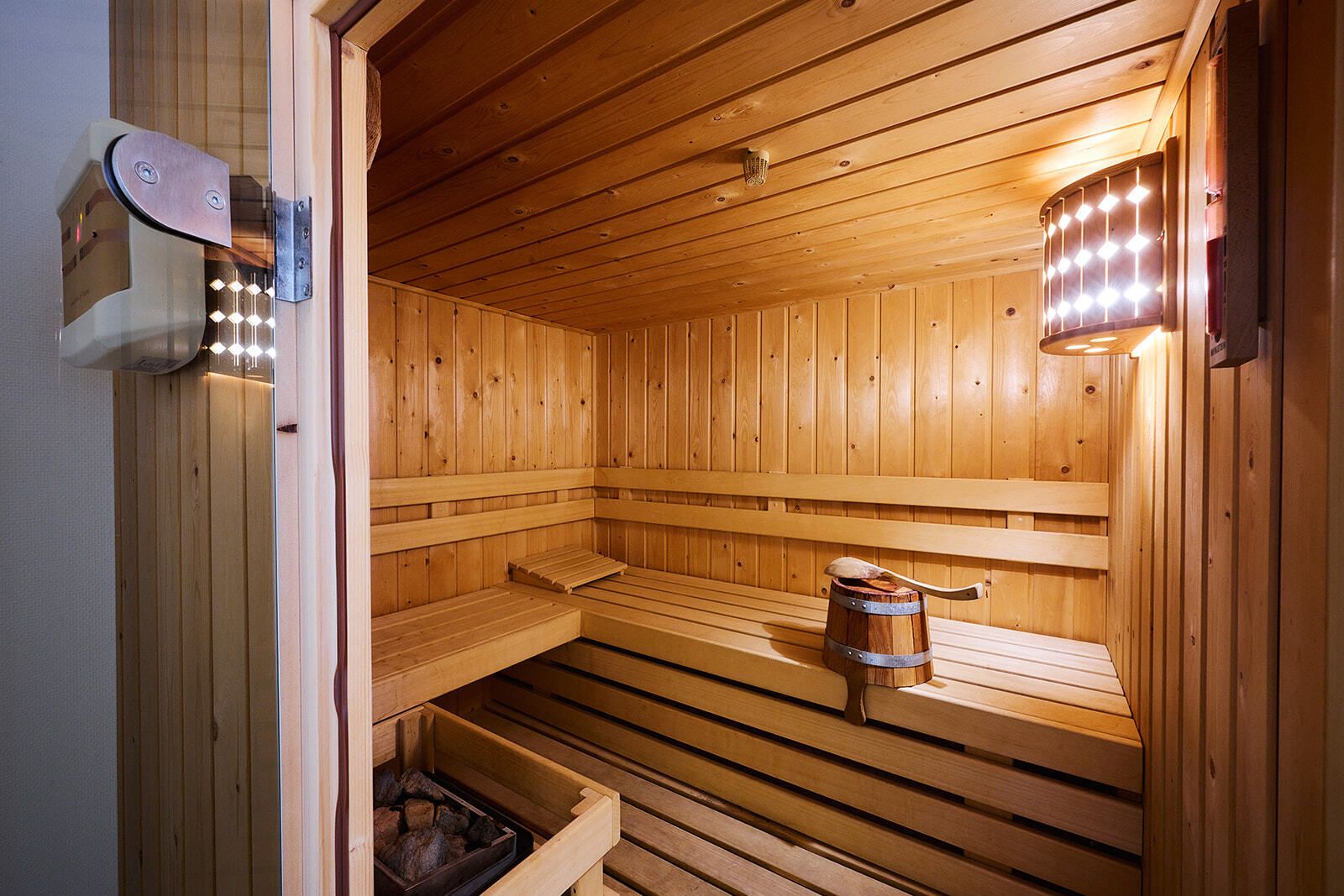 Eine Holzsauna mit Bänken und einem Eimer.