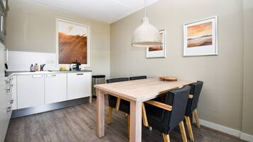A modern kitchen with white cabinets, a wooden dining table, and black chairs.