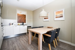 A modern kitchen with white cabinets, a wooden dining table, and black chairs.