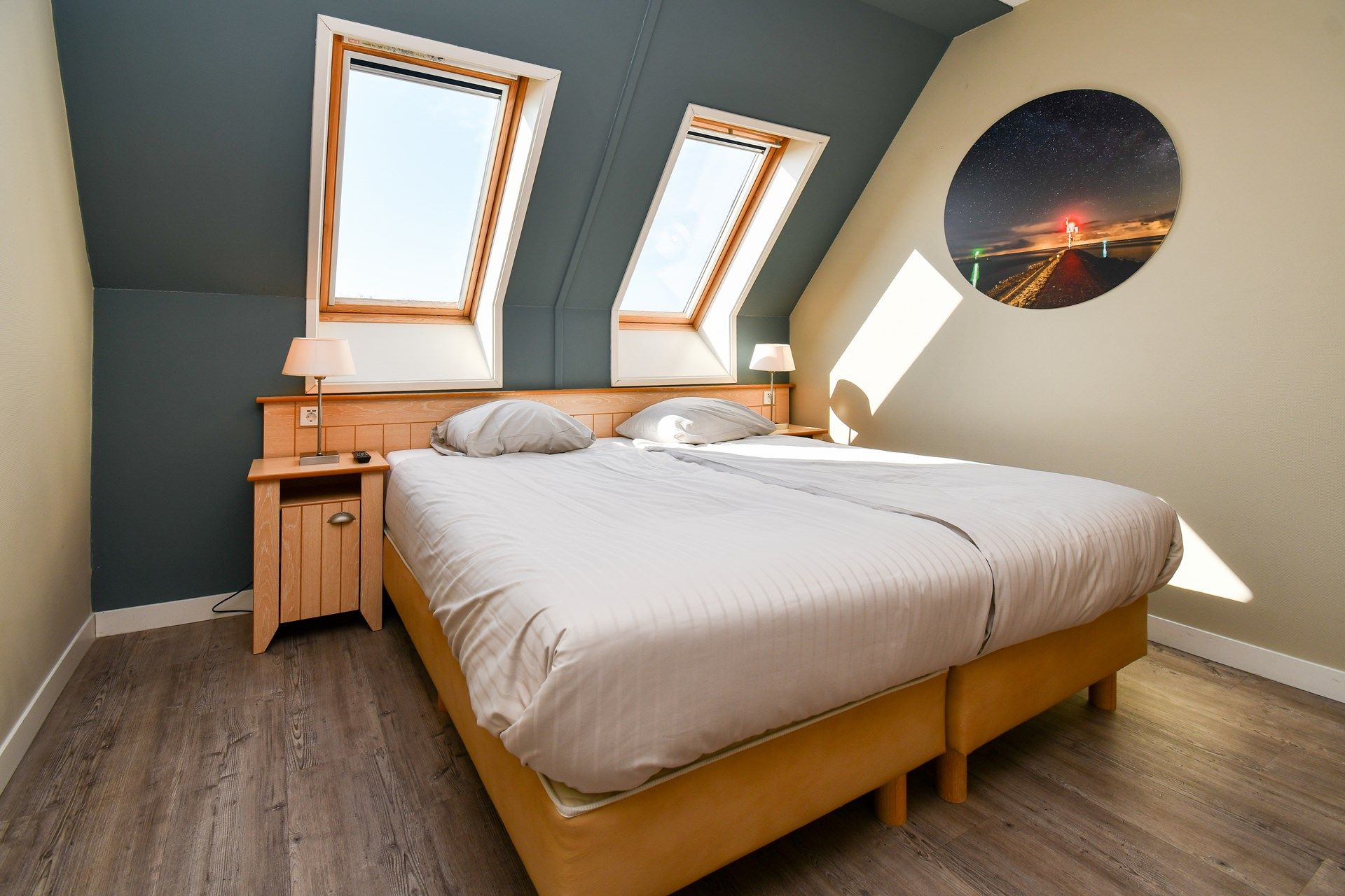 Un dormitorio con una cama, dos mesitas de noche, una lámpara y un adorno circular en la pared.