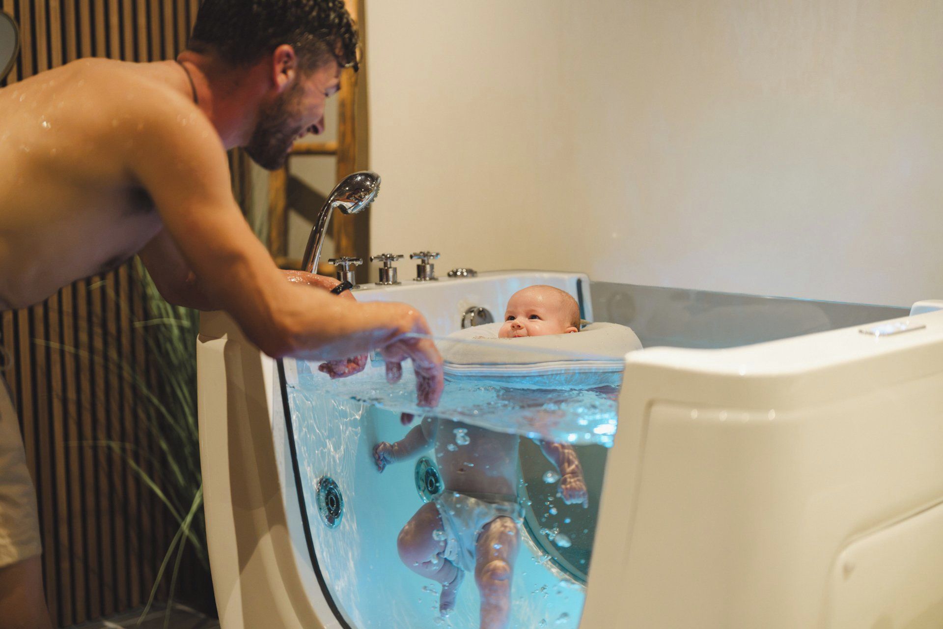 Eine Person wäscht ein Baby in einer Badewanne.