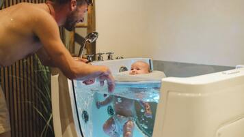 Eine Person wäscht ein Baby in einer Badewanne.