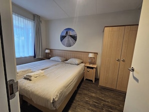 A hotel room with a bed, bedside tables, a wardrobe, and a wall-mounted picture. - This beautiful apartment is ideal for a stay with friends or with the whole family. The space of this apartment gives you and your company enough freedom for a pleasant stay. (Midsland)