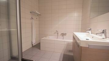 A modern bathroom with a glass shower enclosure, a bathtub, and a vanity with a mirror.