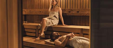 A sauna with wooden benches and a person sitting on one.
