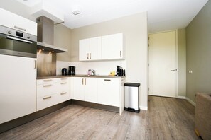 A compact kitchen with white cabinets, a stainless steel range hood, and a coffee maker on the countertop. - This beautiful apartment is ideal for a stay with friends or with the whole family. The space of this apartment gives you and your company enough freedom for a pleasant stay. (Midsland)