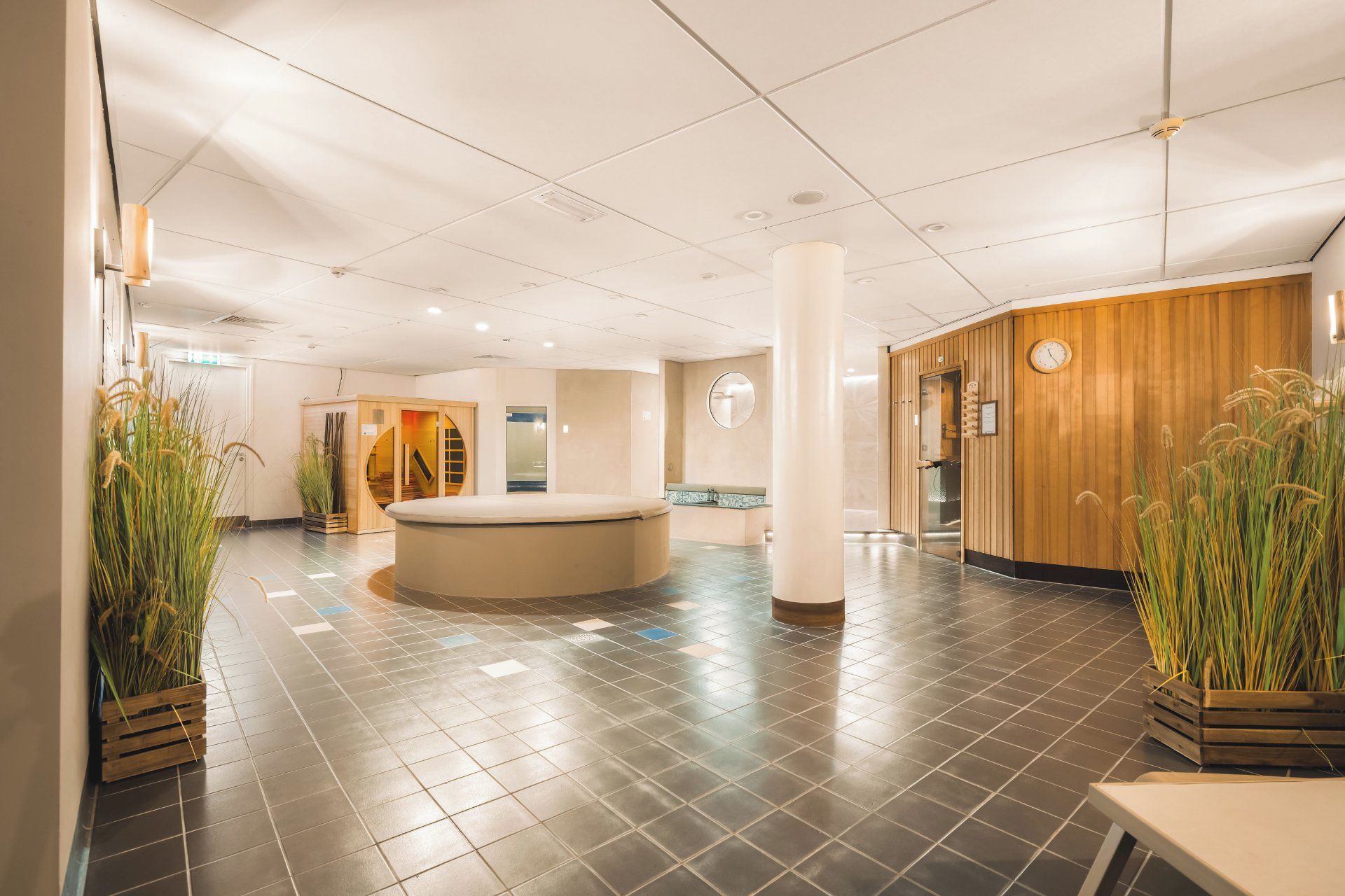 Una hall d'albergo con reception, area salotto e parete in legno con orologio.