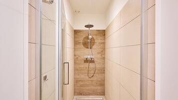 A narrow, modern shower area with a glass door and a wooden wall.