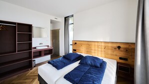 A modern bedroom with a wooden headboard, a bed with blue bedding, a walk-in closet, and a bathroom with a shower. - No shortage of luxury in this exclusive and very spacious apartment. There are five bedrooms, each with its own shower. Enjoy the tranquility and space... (Midsland)