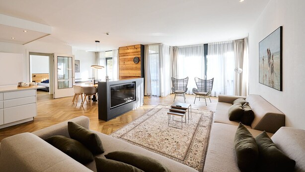 A modern living room with a flat-screen TV, a sofa, a coffee table, and a dining area with chairs. - No shortage of luxury in this exclusive and very spacious apartment. There are five bedrooms, each with its own shower. Enjoy the tranquility and space... (Midsland)