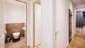 A modern bathroom with a toilet, sink, and wooden panel wall. - No shortage of luxury in this exclusive and very spacious apartment. There are five bedrooms, each with its own shower. Enjoy the tranquility and space... (Midsland)
