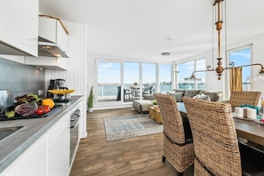 Une cuisine moderne avec un coin repas, de grandes fenêtres et une vue sur la mer.