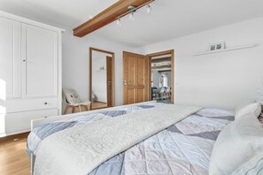 A bedroom with a bed, a wardrobe, a mirror, and a door leading to another room. - Holiday apartment with 1 bedroom (Steinberg)