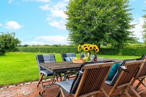 An outdoor dining area with a table and chairs, a basket of fruit, and a vase of sunflowers. - Holiday apartment with 1 bedroom (Steinberg)