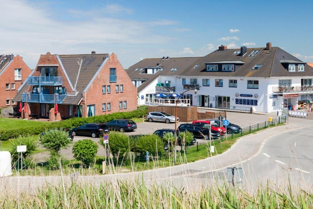 A residential area with houses, a road, and parked cars.