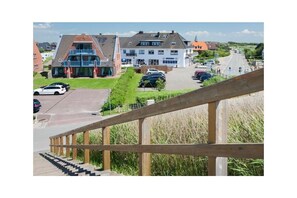 A building with a staircase leading to a parking area. - Utholmer 16 - Lighthouse (St. Peter-Ording)