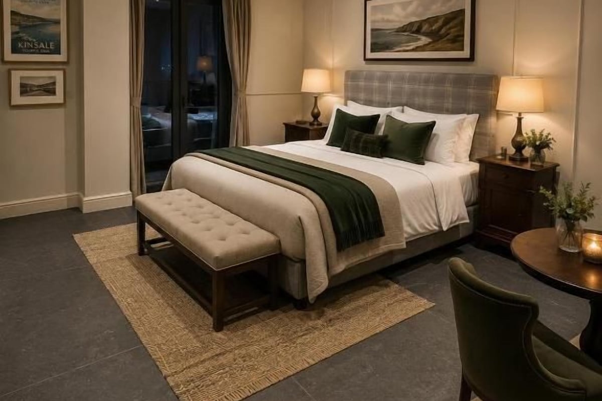 Een hotelkamer met een bed, nachtkastjes, een bankje, een stoel, een tafeltje en uitzicht op het exterieur.