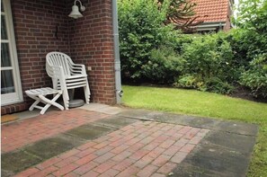 A brick patio with two white plastic chairs and a small table. - Holiday home in Wittmund with swimming pool (Wittmund)