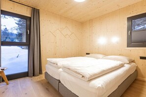 Ein Zimmer mit Holzwänden, einem Bett und einem Blick auf eine verschneite Landschaft.