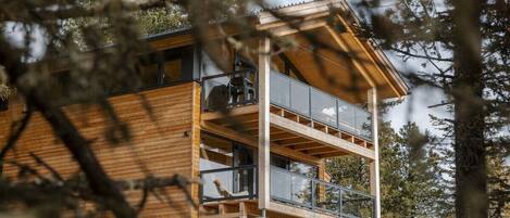 A multi-story wooden cabin with balconies, surrounded by trees.