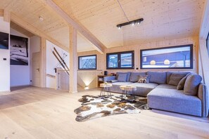 A modern interior with a wooden ceiling, a sofa, a coffee table, and a rug. - Superior Chalet # 26 with Sauna & Hot Tub (Turrach)