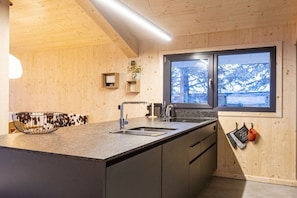 Eine moderne Küche mit Holzvertäfelung, einem großen Fenster und einer eingebauten Spüle.
