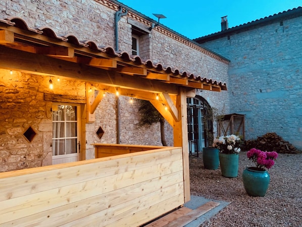 A stone building with a wooden deck and string lights.