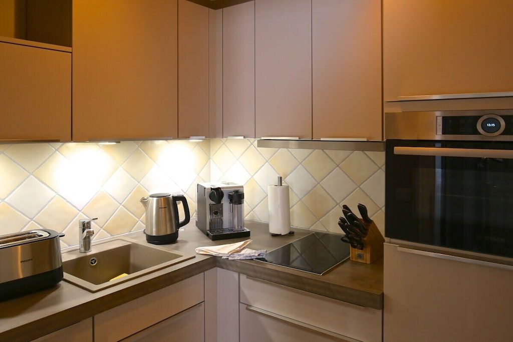 A modern kitchen with a built-in coffee maker, a kettle, and a toaster.