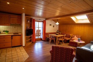 A cozy cabin interior with a dining area, seating, and a kitchen. - Holiday apartment with 2 bedrooms (Ruhpolding)