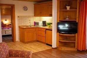 A compact living space with a kitchenette, a television, and a sofa. - Holiday apartment with 2 bedrooms (Ruhpolding)