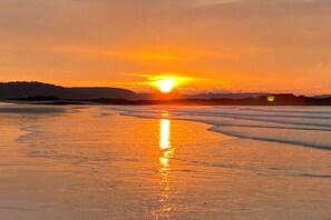 A beach scene with a sunset over the water, reflecting on the wet sand. - Holiday apartment with 2 bedrooms (Ruhpolding)
