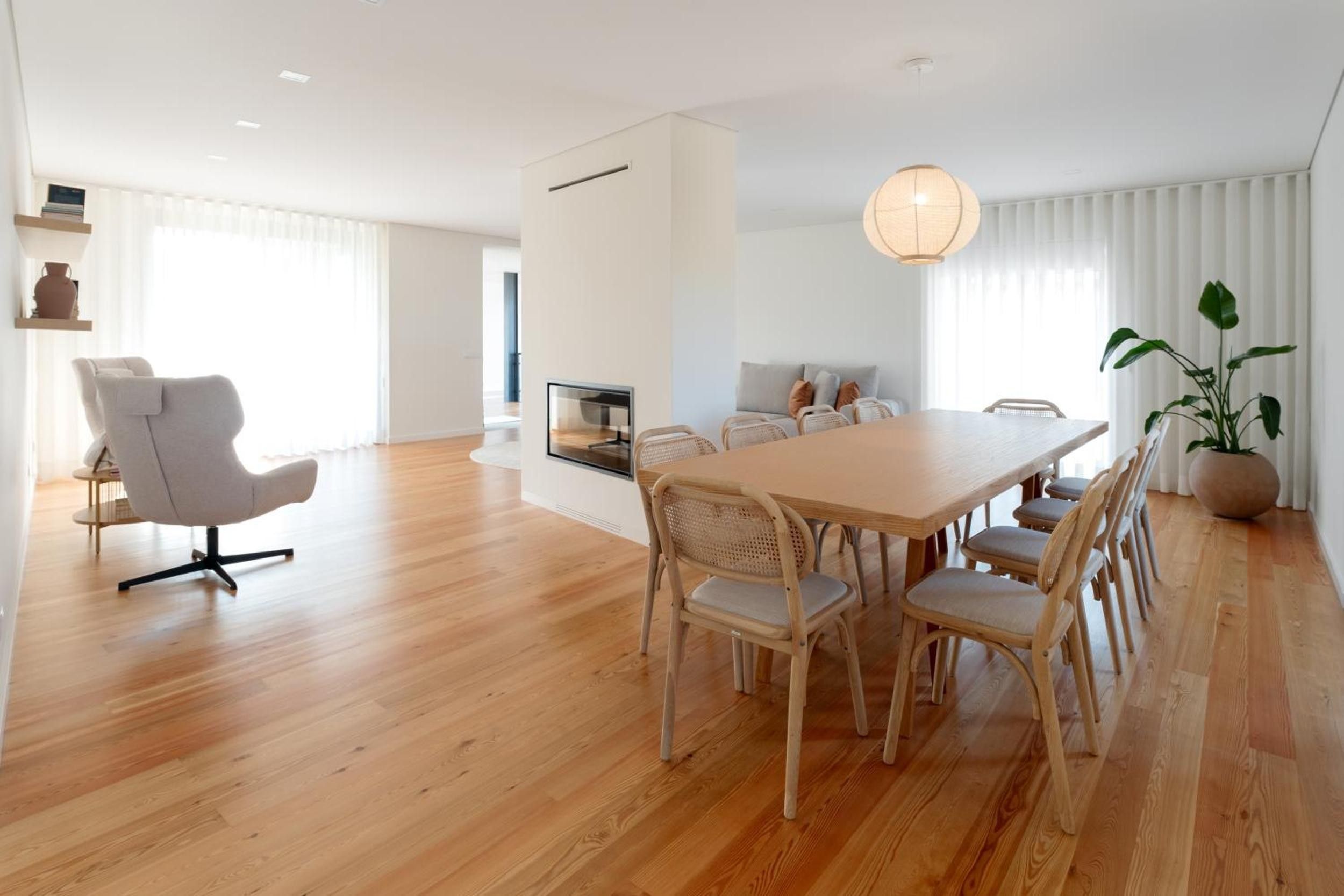 A modern dining area with a wooden table and chairs, a television, and a potted plant.