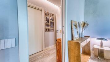 A hallway with a wooden floor, a white door, and a wall with framed pictures.