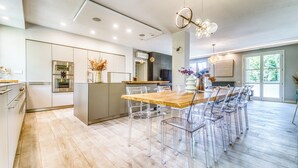 Una cocina moderna con una isla central, sillas traslúcidas y una mesa de comedor de madera.