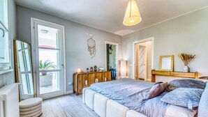 Un dormitorio con una cama grande, un aparador de madera, un espejo y una puerta que da a un balcón.