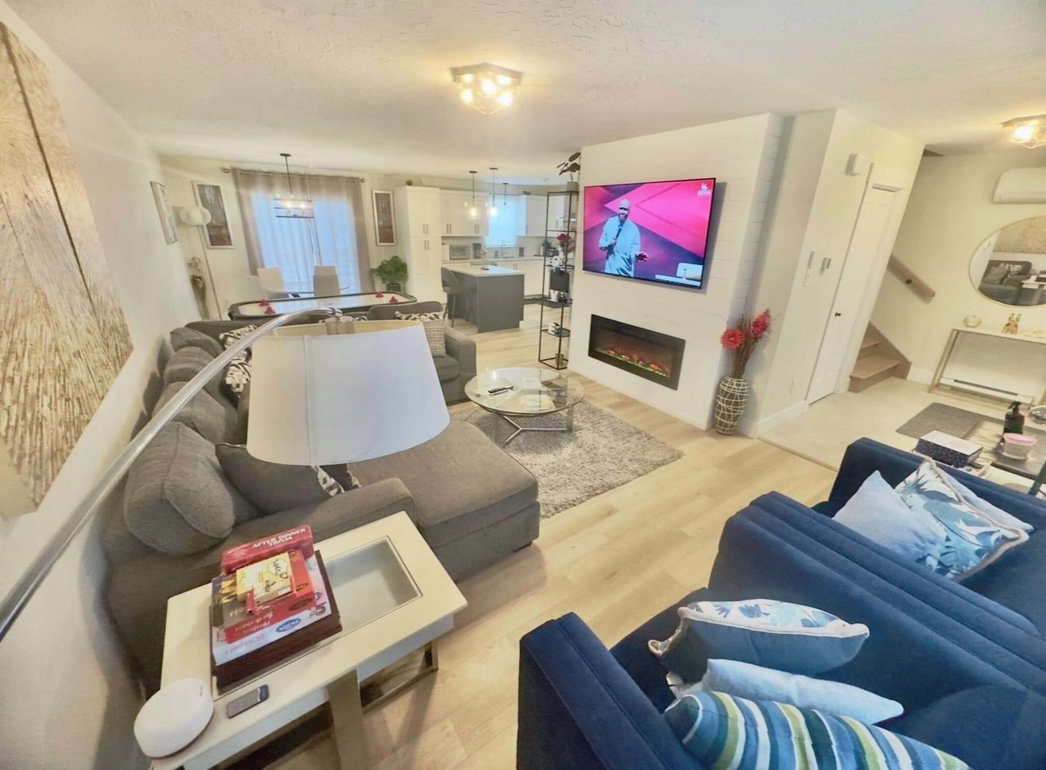 A modern living room with a sofa, armchair, and a TV mounted on the wall.