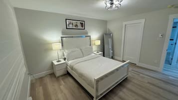 Ein modernes Schlafzimmer mit einem Bett, Nachttischlampen, einem Spiegel und einer Deckenleuchte.