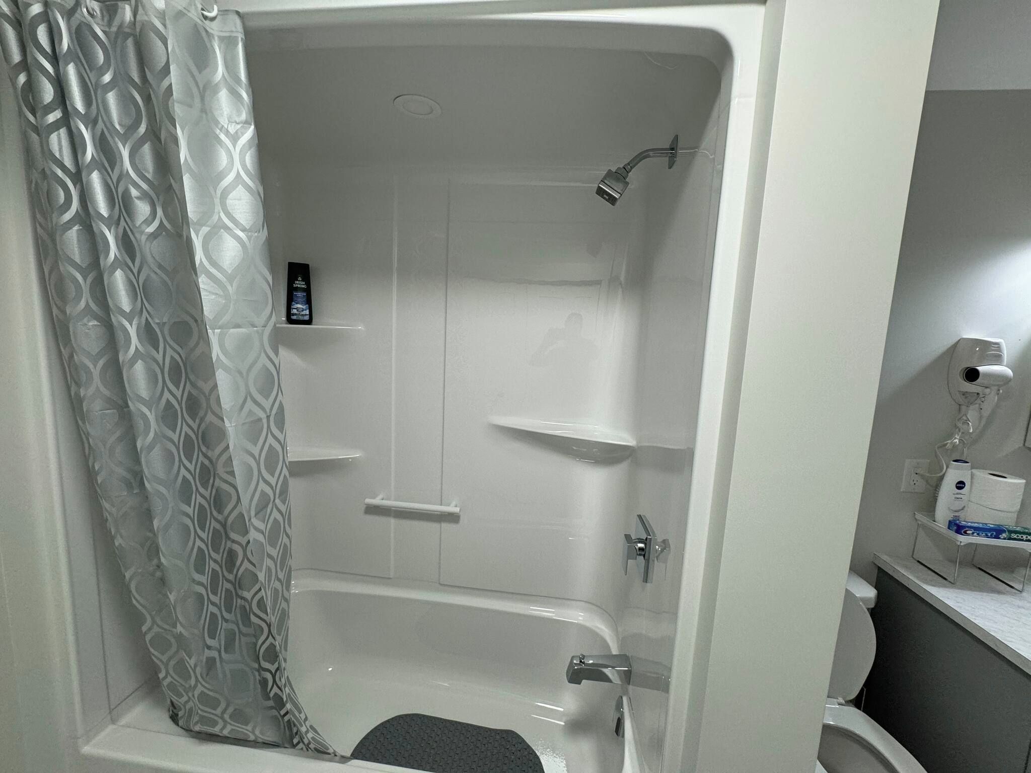A bathroom with a shower, toilet, and a mirror.