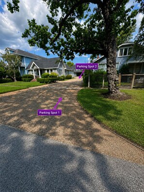 A residential street with two marked parking spots, a tree-lined driveway, and houses with blue siding. - Luxury Loft |Sauna, Hot Tub & Peaceful BalconyView (Houston)