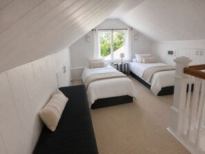 Ein Schlafzimmer mit zwei Betten, einer Bank und einer Treppe.