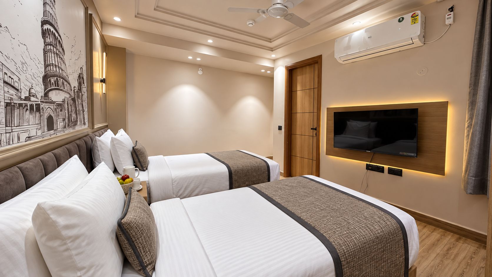 A hotel room with two beds, a flat-screen TV mounted on the wall, an air conditioning unit, and a ceiling fan.